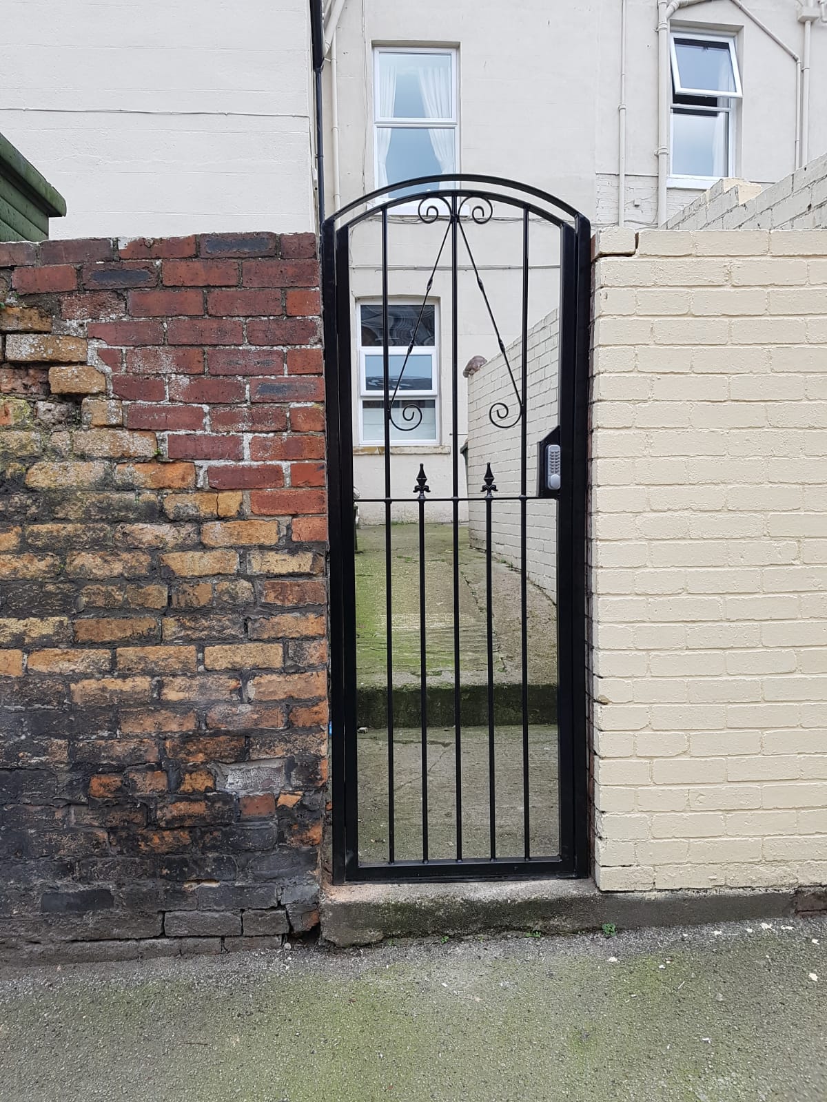 Black ornamental arched side gate with scrollwork
